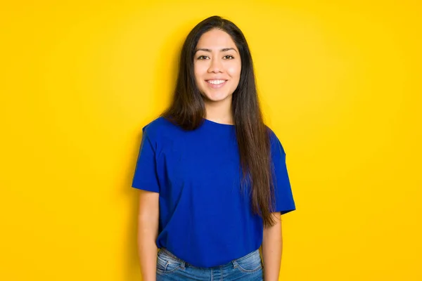 Mooie jonge brunette vrouw staand en glimlachend over geel — Stockfoto