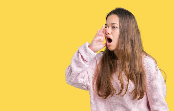 若い美しいブルネット女性の叫び 口の中に手の側に大声で叫んで孤立の背景にピンク冬セーターを着ています 通信の概念 — ストック写真