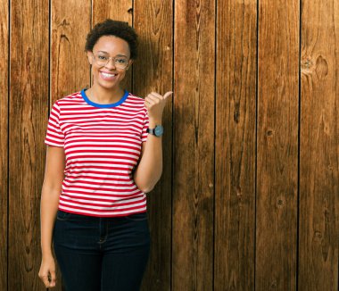 Güzel genç Afro-Amerikan kadın arıyorum ve başparmak yanında yukarıyı mutlu yüz ile gülümseyen izole arka plan üzerinde gözlük.