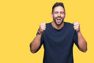 Zafer kutluyor gülümseyen izole arka kolları olan başarı için heyecan üzerinde kazak giyen genç yakışıklı adam kaldırdı. Kazanan kavramı.