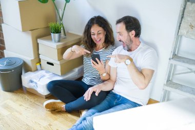 Orta yaş yaşlı çift el ve parmak ile işaret akıllı telefon kullanarak yeni bir eve hareket