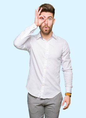 Genç yakışıklı iş adamı ok jest yapıyor sürpriz yüz, göz parmaklarının arasından seyir ile şok. İmansız ifade.