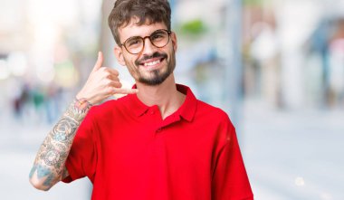 Yakışıklı delikanlı yapıyor gülümseyen izole arka plan üzerinde gözlük telefon hareketi ile el ve parmak telefonda konuşuyor gibi. Kavramları iletişim.