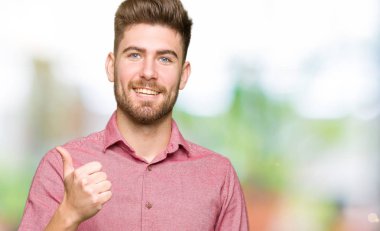 Genç yakışıklı iş casual adam mutlu Yaşasın el hareketini yapıyor. Başarı gösteren kameraya bakarak ifade onaylama.