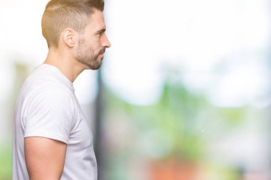 İzole arka tarafına, seyir üzerinde rahat beyaz t-shirt giyen genç adam sakin ol kendine güvenen gülümseme ile doğal yüz pozuyla profili.