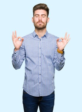 Genç yakışıklı bussines adam rahatla ve gülümseyen gözlerle kapalı parmak jestle meditasyon yapıyor. Yoga kavramı.