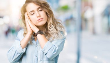 Uyku yorgun hayal ve ellerle birlikte poz ile kapalı gözler gülümseyen izole arka plan üzerinde sarışın güzel genç kadın.