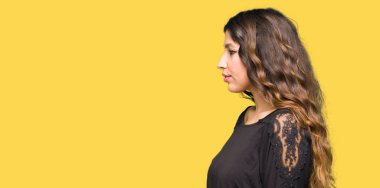 Yan bakan uzun saçlı güzel genç kadın, kendine güvenen gülümseme ile doğal yüzü ile profil poz dinlenmek.