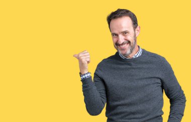 Yakışıklı orta yaş kıdemli adam mutlu yüz görünümlü ve başparmak yukarı ile yan işaret gülümseyen izole arka plan üzerinde bir kazak giyiyor.