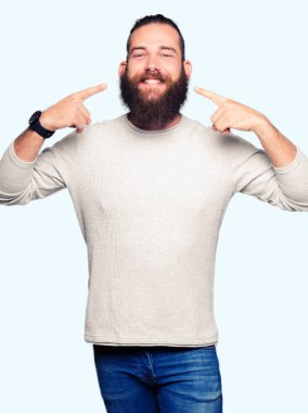 Genç sarışın adam rahat kazak giyen emin gösteren gülümseyerek ve parmakları diş ve ağız ile işaret. Sağlık kavramı.