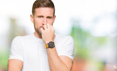 Yakışıklı adam stresli ve gergin ile seyir casual beyaz t-shirt giyen tırnak ısırma dudaklarından eller. Anksiyete sorunu.