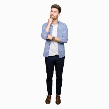 Genç yakışıklı sarışın adam el çenesi ile rahat gömlek giyiyor soru hakkında düşünme, dalgın ifade. Düşünceli bir yüz ile gülümsüyor. Şüphe kavramı.