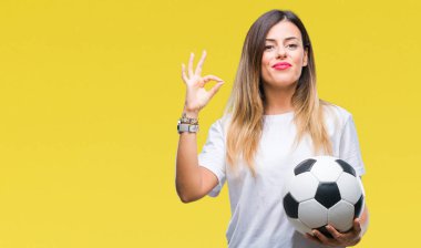 Parmak, mükemmel sembolü ile ok işareti yapıyor izole arka plan üzerinde futbol topu tutan genç güzel kadın