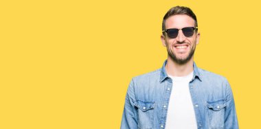 Yakışıklı adam yüzünde mutlu ve güzel bir gülümseme ile moda güneş gözlüğü takıyor. Şanslı kişi.