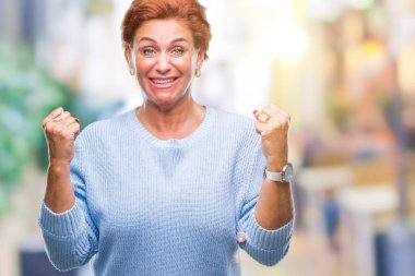 Atrractive üst düzey beyaz Kızıl saçlı kadın kutluyor izole arka plan üzerinde şaşırttı ve başarı için kaldırdı kollarını açarak hayret ve gözleri açık. Kazanan kavramı.