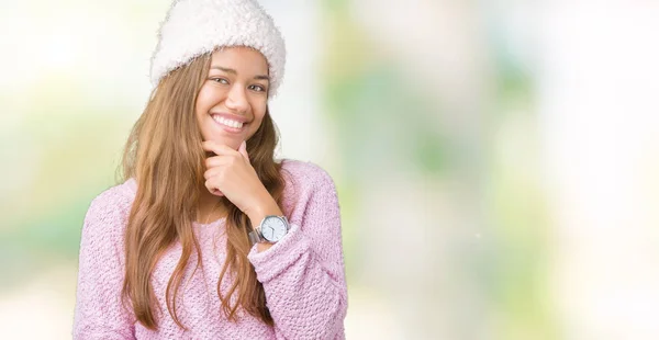 上のセーターと冬の帽子を着ている若い美しいブルネットの女性は 笑顔組んだ腕と手をあごに上げたカメラで自信を持って探して背景を分離しました 前向きに考えてください — ストック写真