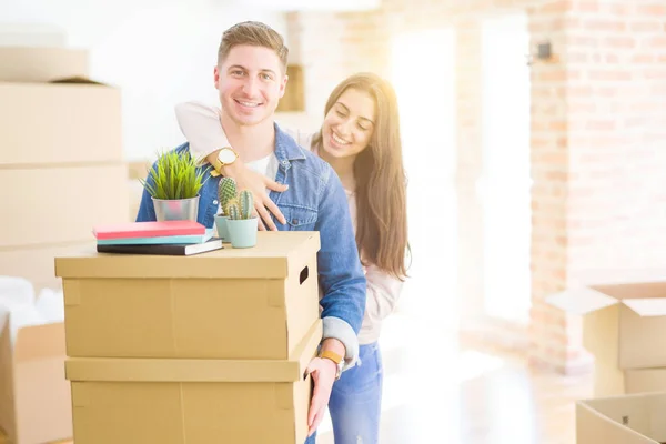 Hermosa pareja joven sonriendo en amor sosteniendo cajas de cartón , — Foto de Stock