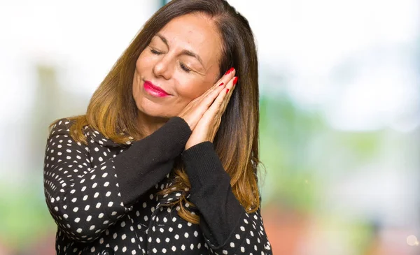 Beautiful middle age woman wearing fashion jacket sleeping tired dreaming and posing with hands together while smiling with closed eyes.