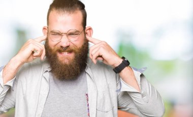 Yüksek sesle müzik gürültü rahatsız ifade parmaklarıyla kulaklarıyla kapsayan gözlüklü genç sarışın adam. Sağır kavramı.