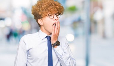 Afro giyen gözlük sıkılmış esneme ile genç yakışıklı iş adamı el ağzıyla kapsayan yorgun. Restless ve uyku hali.