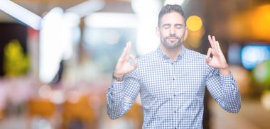 Yakışıklı delikanlı izole arka plan üzerinde dinlenmek ve gülümseyen gözlerle parmak ile meditasyon jest yapıyor kapalı. Yoga kavramı.