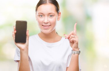 Genç güzel beyaz kadın gösteren smartphone izole arka bir fikirle sürpriz üzerinde ekran ya da gülen yüz, bir numara ile işaret parmağı soru