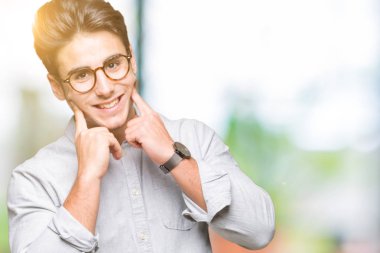 Genç yakışıklı adam gözlük izole üzerinde gülen arka plan açık ağız ile parmak işaret ve neşeli gülümseme zorlamadan