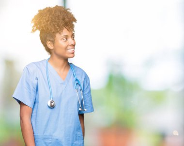 İzole arka plan uzak tarafına gülümseme ile yüzünde, doğal ifade seyir üzerinde genç Afro-Amerikan doktor kadın. Kendine güvenen gülüyor.