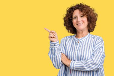 Yüzünde büyük bir gülümseme ile izole arka plan üzerinde Lacivert gömlek giyen güzel orta ager kıdemli kadın, kamera bakarak yan el ve parmak ile işaret.