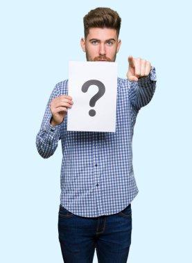 Soru işareti kamera ve size parmak ile işaret ile yakışıklı delikanlı holding kağıt, el işareti, pozitif ve kendinden emin bir jest ön