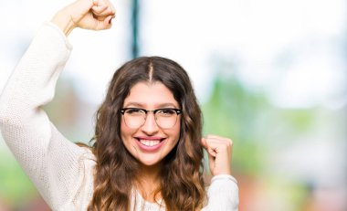 Gülümseyen ve başarı için çığlık çok mutlu ve heyecanlı kaldırdı, silah ile kazanan jest yapıyor gözlüklü genç güzel kadın. Kutlama kavramı.