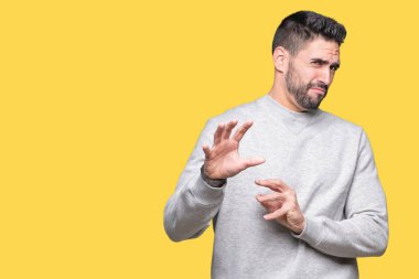 İzole arka plan üzerinde sweatshirt giyen genç yakışıklı adam tiksinti ifadesi, memnun ve korkulu tiksinti yüz yapıyorsun çünkü nefret tepki. Elleriyle kaldırdı. Sinir bozucu kavramı.