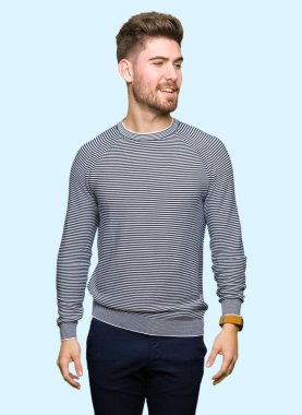 Yüz, doğal ifade gülümseme ile kenara bakarak çizgili kazak giyen genç yakışıklı adam. Güven gülüyor.