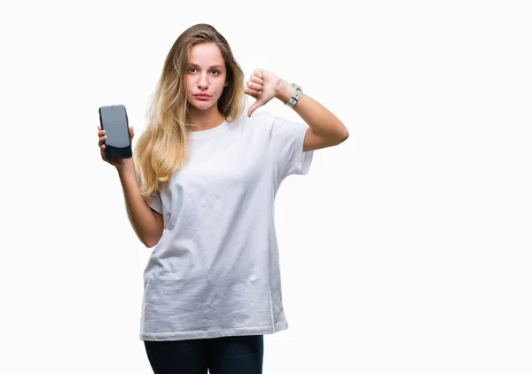 年轻美丽的金发碧眼的女人显示屏幕上的智能手机与愤怒的脸 负面的迹象显示不喜欢大拇指下来 拒绝的概念 — 图库照片