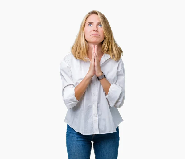 Beautiful young business woman over isolated background begging and praying with hands together with hope expression on face very emotional and worried. Asking for forgiveness. Religion concept.