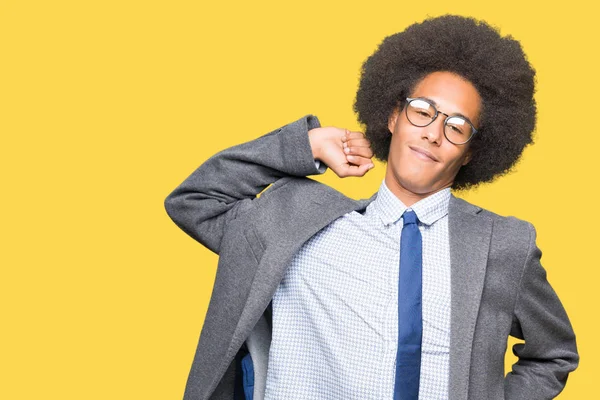 Young african american business man with afro hair wearing glasses stretching back, tired and relaxed, sleepy and yawning for early morning