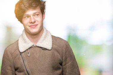 Yakışıklı delikanlı görünümlü yan ve dik dik bakma uzağa düşünce gülümseyen izole arka plan üzerinde kış palto giyiyor.