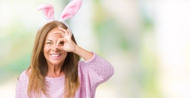 Izole arka plan üzerinde paskalya tavşan kulakları giyen orta yaş esmer kadın el gülümseyerek ok jest yapıyor, mutlu yüz ile parmaklardan bakan göz.