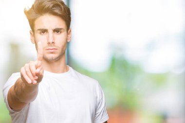Beyaz t-shirt üzerinde izole giyen genç yakışıklı adam arka plan işaret parmağını ve kızgın ifade ile