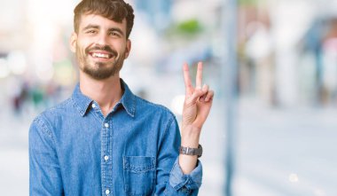 Mutlu yüz zafer işareti yaparken kameraya göz kırpıyor ile gülümseyen izole arka plan üzerinde genç yakışıklı adam. İki numaralı.