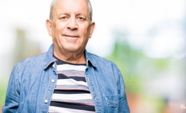 Yüzünde ciddi bir ifade ile kot ceket giyen yakışıklı yaşlı adam. Kameraya basit ve doğal bir bakış.