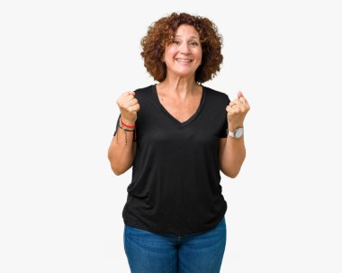 İzole arka plan üzerinde güzel orta ager kıdemli kadın şaşırttı ve silah kaldırdı ve açık gözleri ile başarı için hayran kutluyor. Kazanan kavramı.