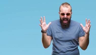 Genç beyaz hipster adam kızgın ve silah ile başarı için deli izole arka plan kutluyor üzerinde güneş gözlüğü takıyor kaldırdı ve heyecanlı çığlık gözler kapalı. Kazanan kavramı