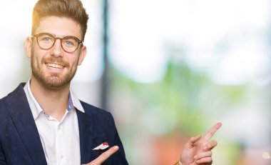 Gülümseyen ve iki elleri ve parmakları ile tarafına işaret kamera bakarak gözlüklü genç yakışıklı iş adamı.