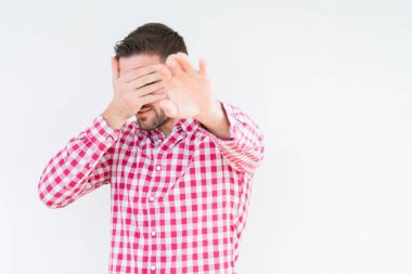 İzole edilmiş arka planda tişört giyen genç yakışıklı adam elleriyle gözlerini kapatıyor ve üzgün ve korku ifadeleriyle dur hareketi yapıyor. Utanç verici ve olumsuz bir kavram..