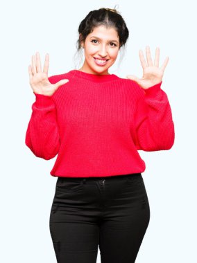 Kırmızı kazak ve gösterilen ve parmakları ile işaret topuz giyen genç güzel kadın kendinden emin ve mutlu gülümseyerek süre on numara.