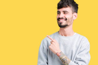 İzole arka neşeli bir gülümseme ile el ve parmak kadar yan yüzünde mutlu ve doğal ifade ile işaret yüz üzerinden sweatshirt giyen genç yakışıklı adam