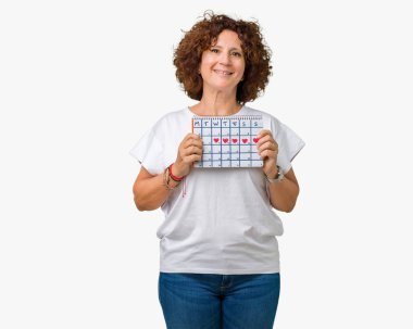 Adet takvim izole arka plan üzerinde duran ve diş gösterilen kendine güvenen bir gülümsemeyle gülümseyerek mutlu bir yüz tutan orta ager üst düzey kadın