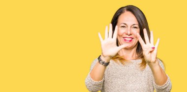 Güzel orta yaş kadın gösteren moda kazak giyen ve parmak sayısı dokuz ile işaret ederken emin ve mutlu gülümseyen.