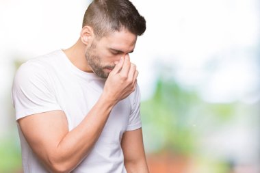 İzole arka plan yorgun sürtünme burun ve göz yorgunluğu ve baş ağrısı duygu üzerinde rahat beyaz t-shirt giyen genç adam. Stres ve hayal kırıklığı kavramı.